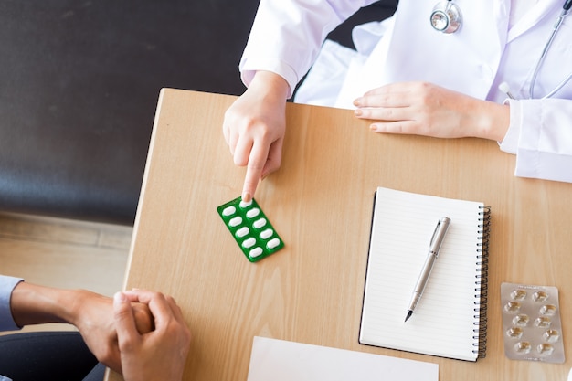  doctor hand holding tablet of drug and explain to patient in hospital room.