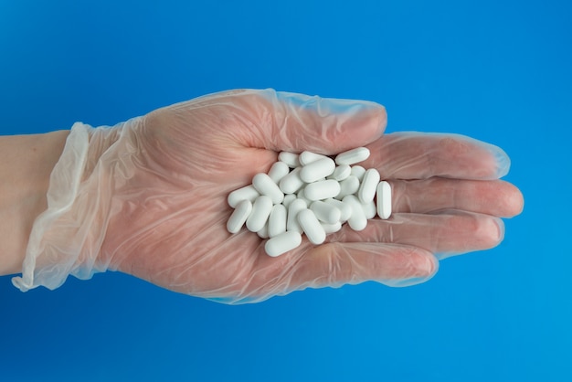 Doctor hand in medical glove holds lots of white pills. Overdose conception