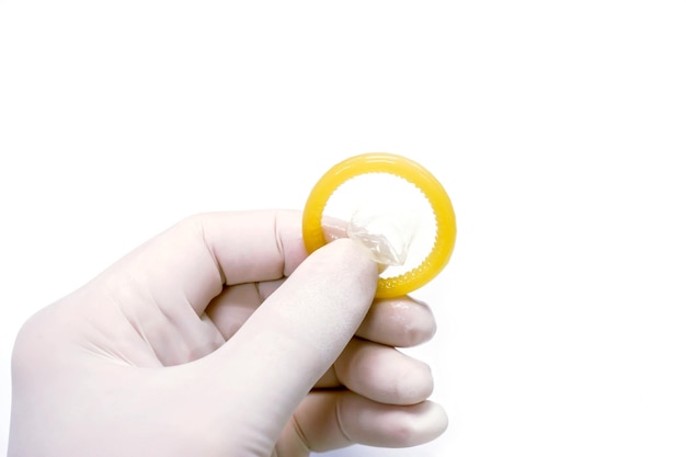 Рука доктора в медицинской латексной перчатке берет презерватив на белом фоне