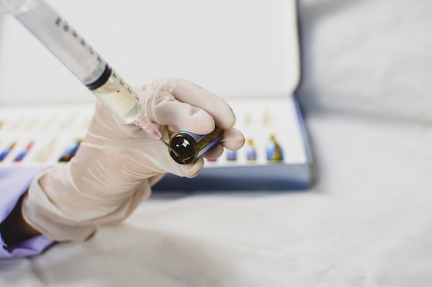 Photo the doctor hand using syringe sucking medicine from drug bottle.