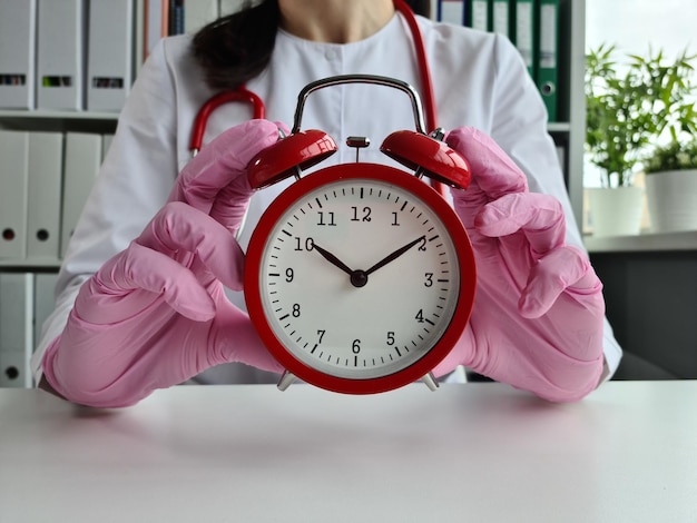 Doctor hand with an alarm clock and health insurance time