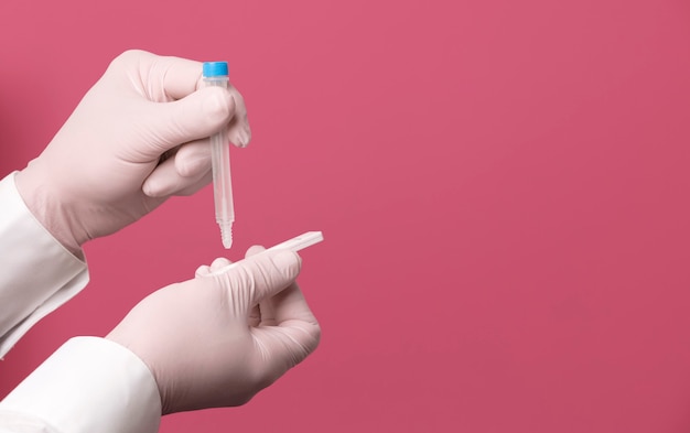 Рука врача с экспресс-тестом на коронавирус на простом фоне