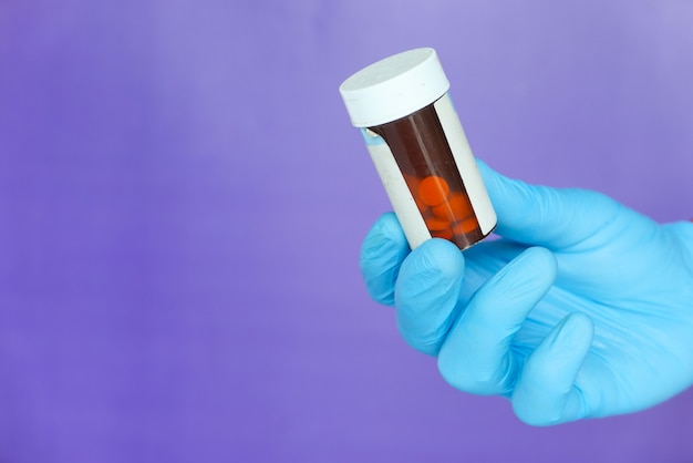 Doctor hand with medical gloves holding pill bottle