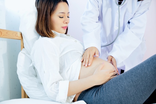 Photo doctor hand with stethoscope on stomach of pregnancy women in the hospital.