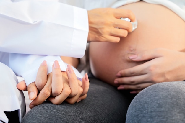 Photo doctor hand with stethoscope on stomach of pregnancy women in the hospital.