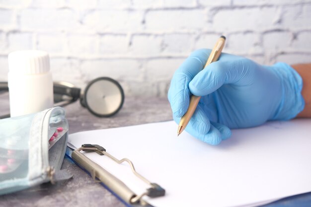 Doctor hand writing prescription on desk close up