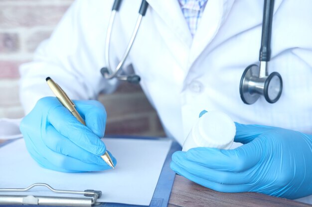 Doctor hand writing prescription on desk close up