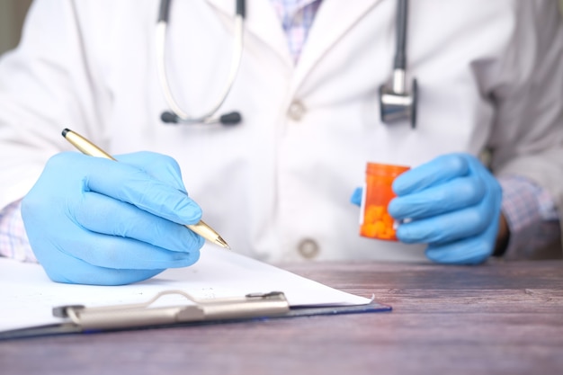 Doctor hand writing prescription on desk close up