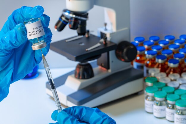 Doctor hands in blue gloves holding Sars-cov-2 vaccine vial