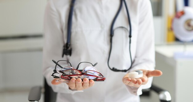 Doctor hands hold choice of glasses and contact lenses