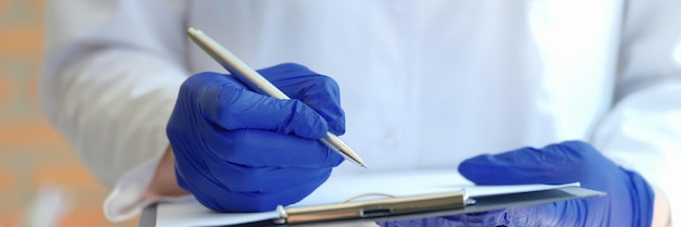 Руки врача держат буфер обмена с ручкой и регистрационным документом пациента в регистратуре клиники