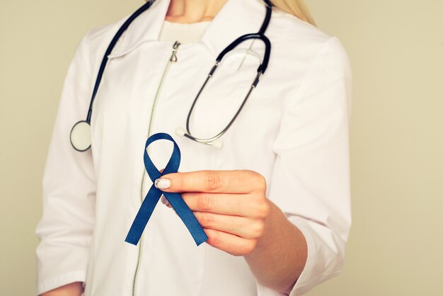 Doctor hands holding blue ribbon, diabetes and Colorectal Cancer Awareness 