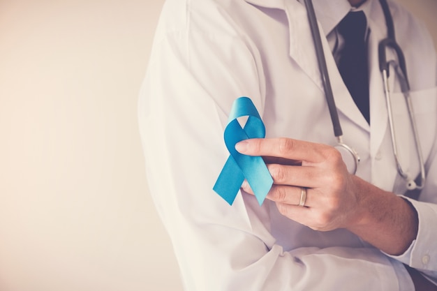 Photo doctor hands holding blue ribbon,  movember, prostate cancer awareness