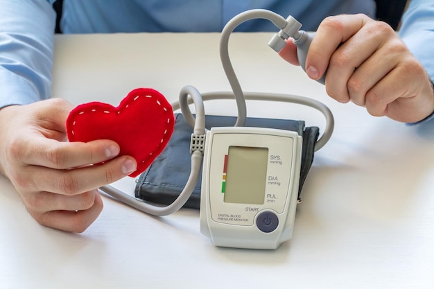 Doctor hands holding tonometer and heart figurine