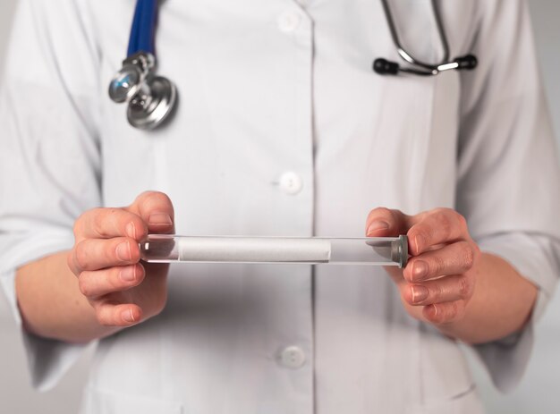 Doctor hands holding tranparent glass test tube close up on background of uniform.