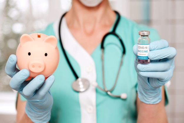 Doctor hands holds vaccine vial and piggy bank