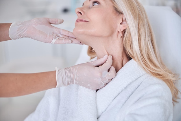 Foto mani del medico in guanti protettivi che guardano alla pelle del paziente nell'armadietto dermatologico