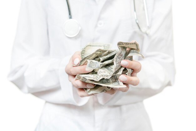 doctor hands in white coat holding a pile of crumpled dollars isolated on white background