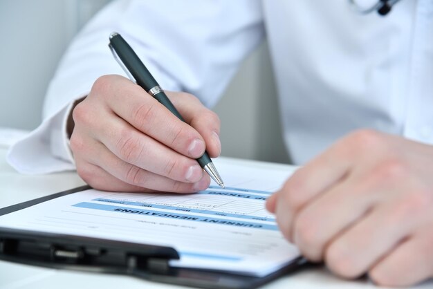 Doctor hands writing on clipboard in medical office