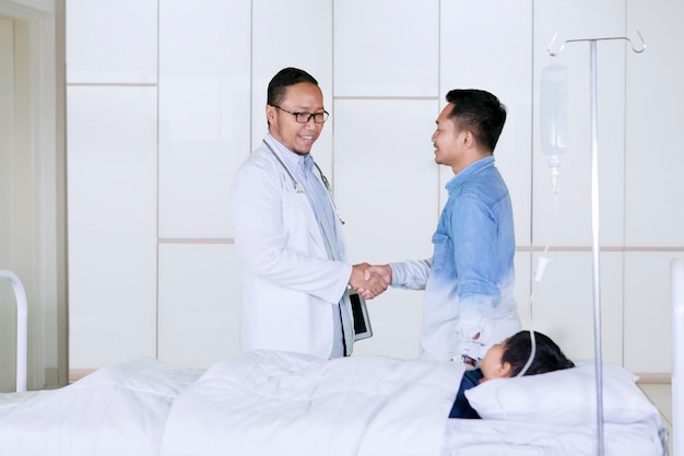 Doctor handshaking with father patient in hospital