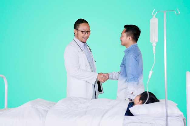 Doctor handshaking with father patient on studio