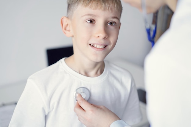 Doctor and happy smiling child boy patient at usual medical inspection in clinic. Medicine, healthcare concepts