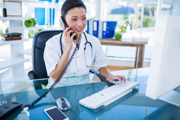 Photo doctor having phone call and using her computer