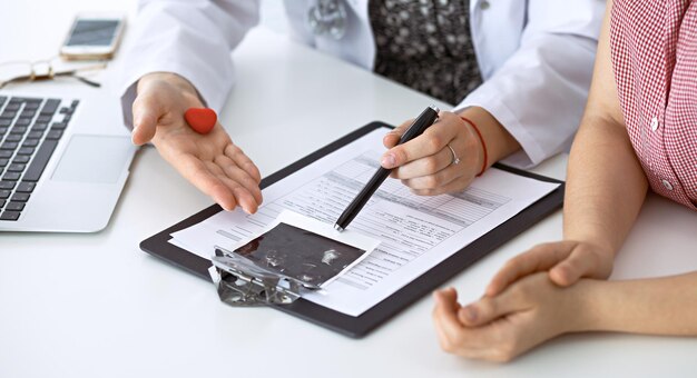 Doctor heart and patient. Physician discussing health exam with future mother. Medicine, healthcare and pregnancy concept.