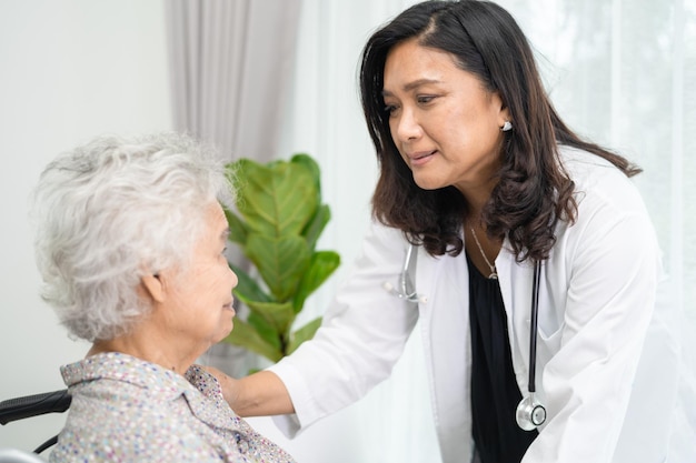 Doctor help and care Asian elderly woman patient sitting on wheelchair at nursing hospital