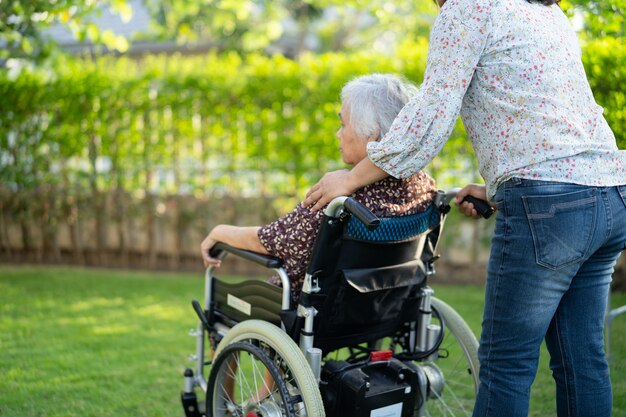 Doctor help and care Asian senior or elderly old lady woman patient sitting on wheelchair at park in nursing hospital ward, healthy strong medical concept.