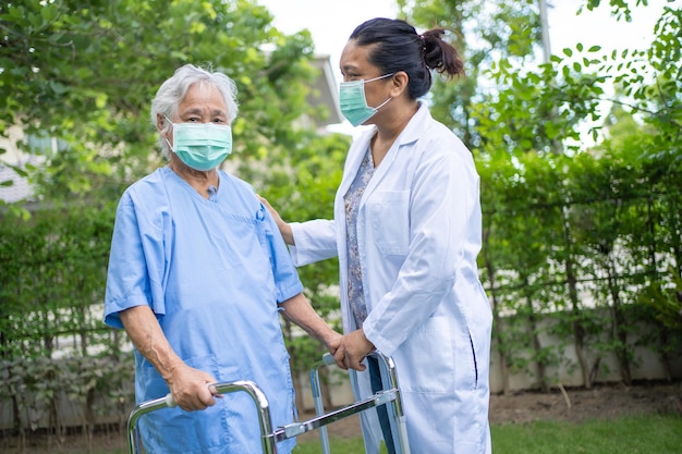 Il medico aiuta e cura la donna anziana o anziana asiatica usa il camminatore con una buona salute mentre cammina al parco in una felice vacanza fresca.