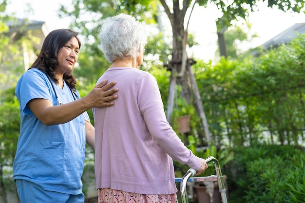 의사의 도움과 보살핌 아시아 노인이나 노부인은 행복한 휴일에 공원을 걷는 동안 건강이 좋은 워커를 사용합니다.