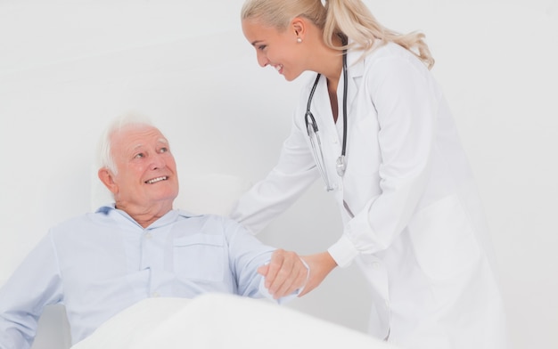Medico che aiuta l'uomo anziano a sedersi