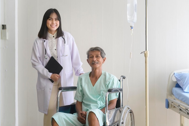 病院で車椅子に移動するシニア患者の男性を支援する医師