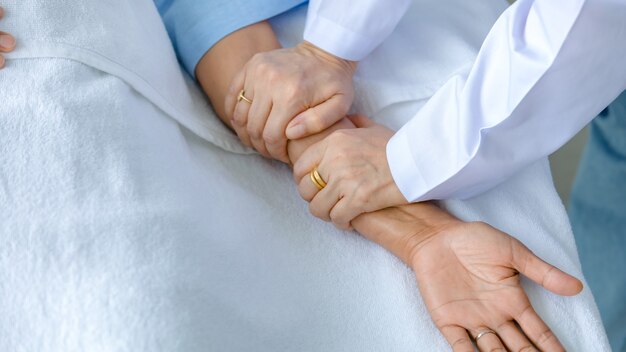 Doctor hold hand of patient on bed in hospital and checkup nervous system for cure and treatment. Concept of Guillain barre syndrome and numb hands disease or vaccine side effect.