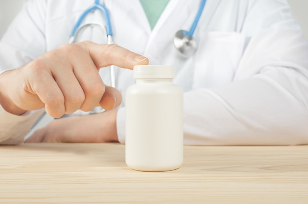 Doctor holding bottle of tablets or pills with blank white label for treatment of illness or injury