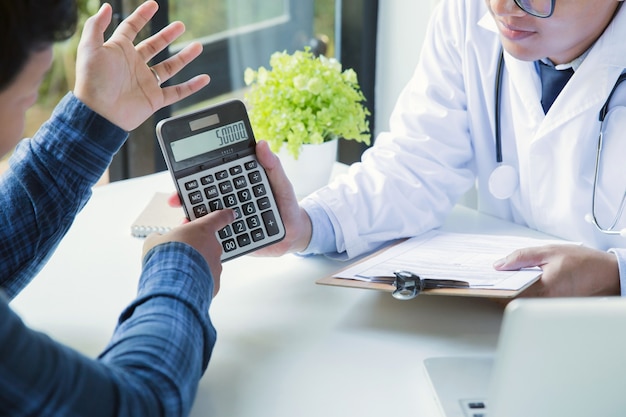 Doctor holding calculator to explain the expenses to the patient.