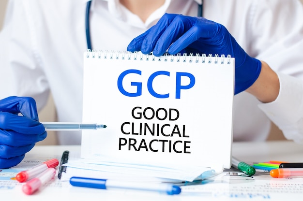 テキストGCPのカードを持っている医師-GOODCLINICAL PRACTICE、医療コンセプトの略