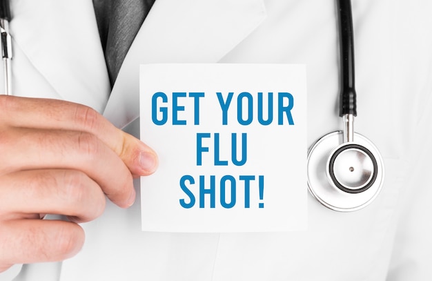 Doctor holding a card with text Get your flu shot, medical concept