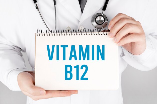 Medico in possesso di una scheda con testo vitamina b12, concetto medico Foto Premium