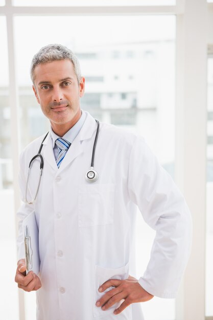 Doctor holding clipboard smiling at camera 