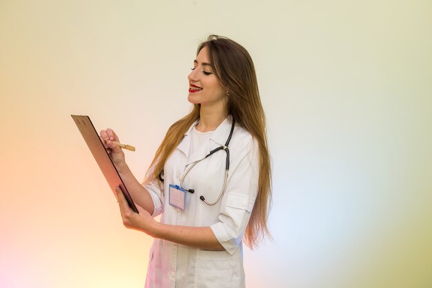 Doctor holding clipboard with pen. Pretty woman in medical form smiling