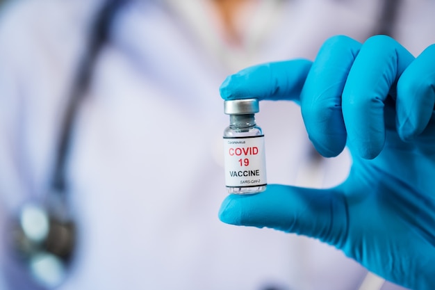 注射薬用のコロナウイルス（Covid-19）ワクチンボトルを持っている医師