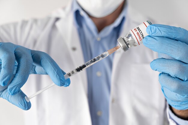 Doctor holding coronavirus vaccine and syringe close up