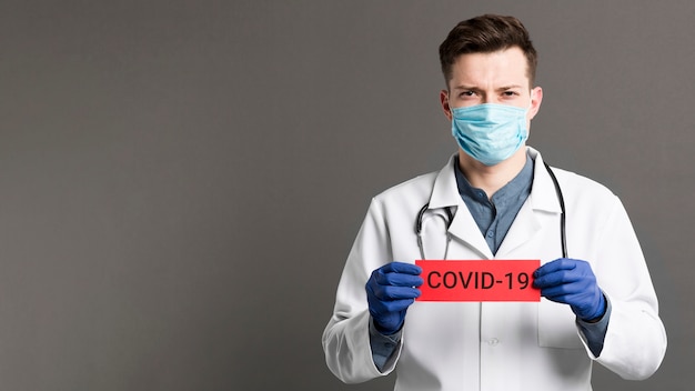 Foto medico che tiene lo spazio della copia della carta covid-19