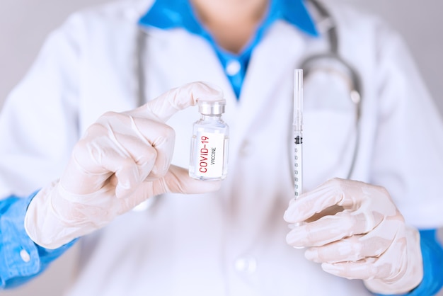 Doctor holding COVID-19 vaccine and syringe for treat and cure