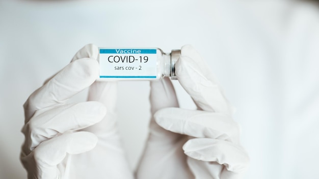 COVID19 백신을 들고 의사는 흰색 바탕에 닫습니다.