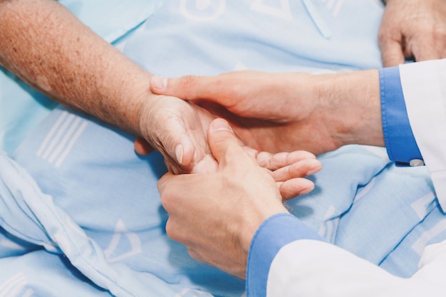 Doctor holding elderly person hand with care in hospital.healthcare and medicine