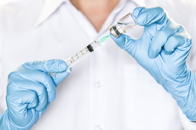 Doctor holding flu, measles injection vaccine and  syringe with needle for baby vaccination 