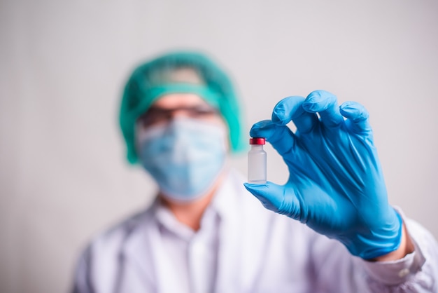 Doctor holding flu vaccine on beige background, medicine and drug concept. Vaccination against Coronavirus covid-19 pandemic.